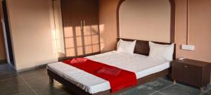 a bedroom with a bed with a red blanket on it at Minakshi Resort in Loni Kand