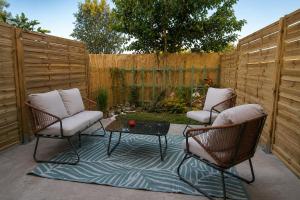 a patio with two chairs and a table and a fence at Le Nid des Wallabys in Monchy-le-Preux