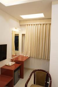 a room with a desk and a chair and a television at Hotel Maruti in Mandsaur +25 photos