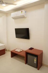 a room with a flat screen tv and a table at Hotel Maruti in Mandsaur