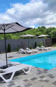 a pool with umbrellas and lounge chairs next to a pool at OLENEVO Park Houses in Olenʼovo