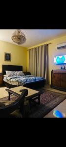 a bedroom with a bed and a table and a chandelier at Pyramids Heritage suites in Ghaţāţī