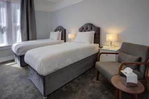 a hotel room with two beds and a chair at Best Western Stoke on Trent City Centre Hotel in Stoke on Trent