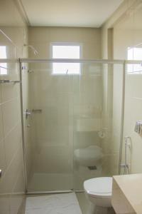 uma casa de banho com uma cabina de duche em vidro e um WC. em Patos Hotel em Patos de Minas