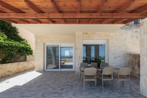 a patio with a table and chairs and a fireplace at Azura Villa #Skgbnb in Mesochórion