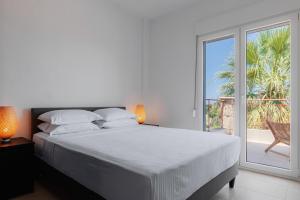 a white bedroom with a bed and a large window at Azura Villa #Skgbnb in Mesochórion +56 photos