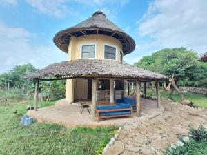 a house with a thatched roof and a patio at Tiny house, kitchen downstairs in Shimoni