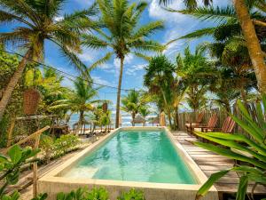 a swimming pool with palm trees and a resort at Dos Ceibas Tulum - Feel Good Hotel in Tulum