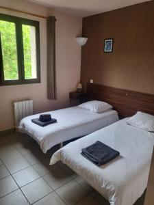 two beds in a hotel room with towels on them at Auberge du Tarnon in Vébron +5 photos
