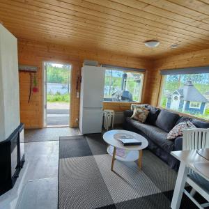 a living room with a couch and a refrigerator at Lomamökki seitsemisen kansallispuiston lähellä in Aurekoski