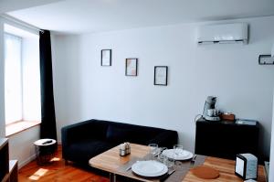 a living room with a table and a black couch at Dormir près de Brioude - studio 'esprit cocon' in Fontannes +8 photos