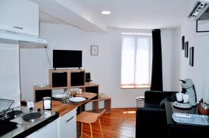 a living room with a kitchen and a living room with a table at Dormir près de Brioude - studio 'esprit cocon' in Fontannes