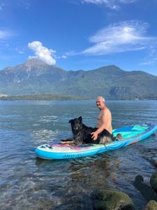a man and a dog sitting on a paddle board in the water at Immobillario - Domus Palmae in Domaso