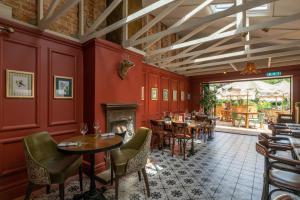 a restaurant with red walls and tables and a fireplace at The Dundas Arms in Kintbury