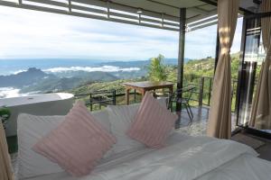 a white couch with pink pillows on a balcony at ฟลายมี ภูทับเบิก in Ban Maeo Thap Boek