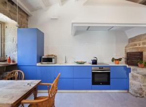 a kitchen with blue cabinets and a wooden table at Casa Caseiros, Couso in Gondomar