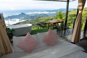 a white couch with pink pillows on a balcony with a bath tub at ฟลายมี ภูทับเบิก in Ban Maeo Thap Boek