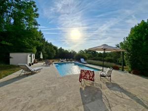 a swimming pool with two chairs and an umbrella at Casa Oksana in Castelnau-de-Montratier