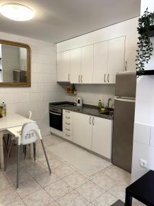 a kitchen with white cabinets and a table and a refrigerator at Flat with nice view in Gualtar, Braga in Braga +10 photos