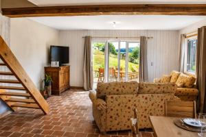 a living room with a couch and a television at Cottage de charme avec piscine et vue panoramique - 6-8 pers Pays d'Auge in Vimoutiers