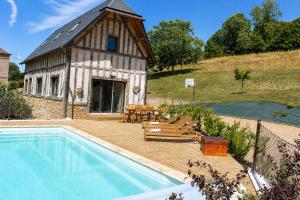 a house with a wooden deck next to a swimming pool at Cottage de charme avec piscine et vue panoramique - 6-8 pers Pays d'Auge in Vimoutiers