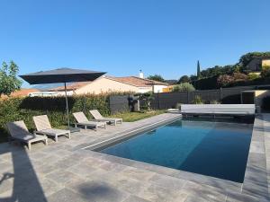 a swimming pool with two chairs and an umbrella and an umbrella at villa récente climatisée avec piscine privée in Vaison-la-Romaine
