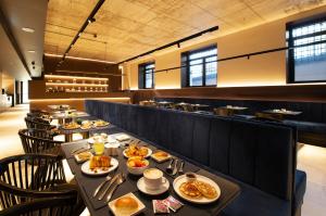 a dining room with a long table with food at Breda Suites Hotel Milano in Milan +23 photos