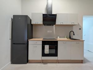 a kitchen with a black refrigerator and white cabinets at Downtown Condo w Huge TV in Zagreb