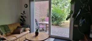 a living room with a couch and a table and a sliding glass door at B&B Even Heukelom - Kamer met Tuin in Afferden