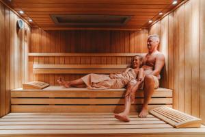 a man and a woman sitting in a sauna at Grand Hotel Praha in Tatranská Lomnica