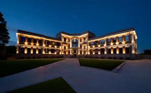 a lit up building with a lawn in front of it at Breda Suites Hotel Milano in Milan