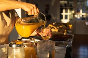 a woman is pouring a glass of orange juice at Hotel El Patio in Garachico