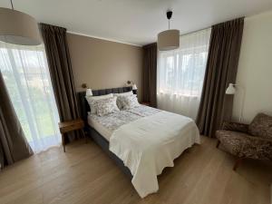 a bedroom with a bed and a chair and windows at Villa Eha in Kuressaare