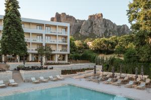 a hotel with a pool with a mountain in the background at Divani Meteora Hotel in Kalabaka