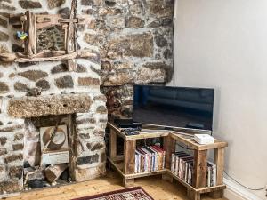 a living room with a tv and a stone wall at Driftwood in St Ives