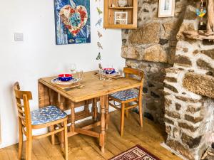 a wooden table and chairs in a room with a stone wall at Driftwood in St Ives