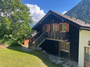 a black house with a balcony and a deck at L'Attique du Vieux-Champex in Orsières