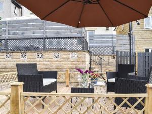 a patio with two chairs and an umbrella at Huddersfield House, Wood View in Huddersfield