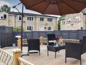 a patio with chairs and an umbrella on a wooden deck at Huddersfield House, Wood View in Huddersfield