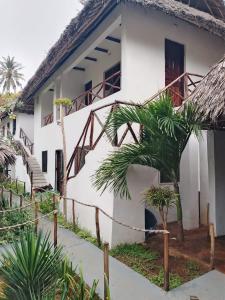 a white house with a palm tree in front of it at Al Mar Bed and Breakfast in Watamu