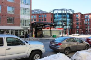 two cars parked in a parking lot in front of buildings at West Broadway Quarters by Thatch in Boston