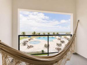 a hammock in a room with a view of a pool at Maragogi Praia Hotel in Maragogi