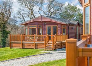 a large wooden cabin with a large deck at Meadow Lakes Holiday Park in St Austell