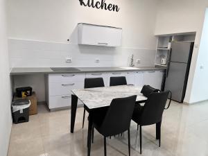 a kitchen with a table and chairs and a refrigerator at הפינה של פנינה במושבה - דירה משפחתית מהממת in Migdal
