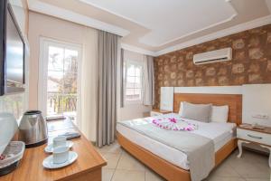 a hotel room with a bed with a flower on it at Nicholas Park Hotel in Oludeniz