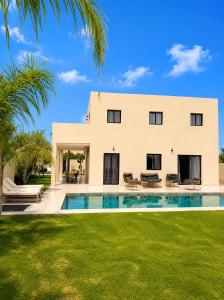 a large white house with a swimming pool in front of it at Villa Elysia in Ech Chaïbat