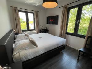 a bedroom with a bed with white sheets and windows at Hôtel Restaurant Lamy in Troisvierges