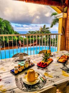 a table with food and a view of a pool at Maison d'hôtes Villa des Mascareignes in Petite Île