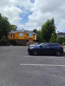 a blue car parked in a parking lot in front of a house at The Véro Townhouse Killarney in Killarney