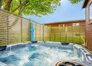 a hot tub in a backyard with a fence at Meadow Lakes Holiday Park in St Austell